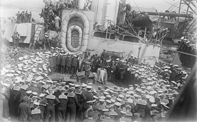 Seeleute drängen sich um den australischen Premierminister The Hon William Morris (Billy) Hughes, als er sie auf dem Deck der HMAS Australia in der Werft in Devon, England, anspricht, 21. Mai 1916
