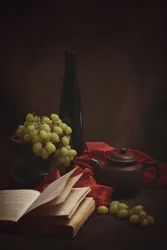 Trauben, altes Buch und Teekanne
