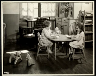 Zwei blinde sehbehinderte Mädchen essen an einem kleinen Tisch mit Puppe bei der New York Association for the Blind, 111 East 59th Street, New York, 1933 (Silbergelatineabzug)