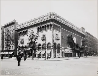 Ein riesiges Theater mit einer aufwendigen Fassade, einschließlich maurischer Bögen und Balkone. Ein großes Schild auf dem Gebäude trägt die Aufschrift „B.S. Moss Regent Theatre Vaudeville & Feature Films“. Ein Werbeschild für Olga Petrova in „The Heart