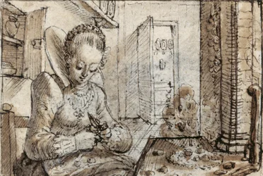 Eine modische junge Frau sitzt an einem Küchentisch und knackt Walnüsse