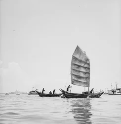 Ein Sampan unter Segel und einer wird im Hafen von Penang gerudert