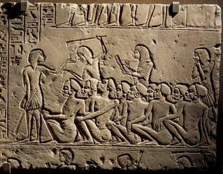 Eine Gruppe von Negroid-Gefangenen, umgeben von Wachen mit Keulen, während ein Schreiber einen Bericht erstellt, Relief aus dem Grab von Horemheb in Saqqara