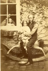 Vater und Tochter auf einem Schaukelpferd mit Bruder und Mutter, die durch das Fenster schauen, 1860er Jahre