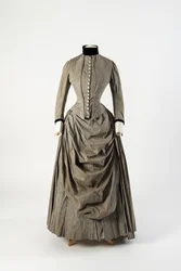 Graues Baumwollkleid mit drapierter Schürzenfront und Besatz aus schwarzem Samt an Kragen und Manschetten, späte 1880er Jahre