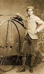 Mann neben seinem Hochrad stehend, um 1890