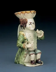 Trinker Toby Krug, sein Hut mit braunem und gelbem gewelltem Rand, sein eingeschnittenes braunes Haar en queue und mit einer weißen Rosette, sitzend mit einem Balusterkrug auf seinem Knie, ca. 1770