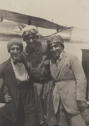 Porträt von drei Männern, die vor einem Flugzeug lächeln