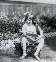 Ein junges Mädchen, Betty, hält eine östliche Indigo-Schlange, während sie auf einem Lederkoffer sitzt, Londoner Zoo, 1924