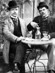 Ein Schlossherr (Ducos) und sein Kutscher sitzen auf der Terrasse eines Cafés und trinken Absinth