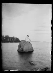 Hugo Simberg sitzt auf einem Stein, Essaari und Suonionsaari im Hintergrund