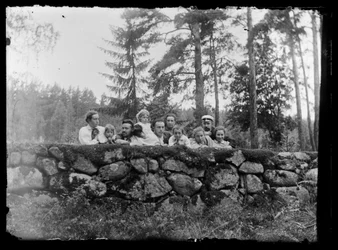 Hugo Simberg mit Geschwistern auf einer Steinmauer