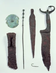 Von oben nach unten: Messer, Speerspitze, Angelhaken, Wäscheklammer, Gürtelplatte und Axt, alle gefunden in Männergräbern in Hallstatt, Eisenzeit