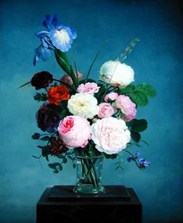 Rosen und eine Iris in einer Glasvase auf einem Marmorsockel