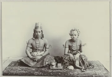 Studio-Porträt eines sitzenden jungen javanischen Mannes und einer Frau, die einen Batik-Sarong tragen