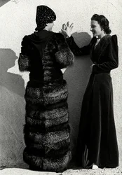 Zwei Modelle präsentieren Kreationen des italienischen Modehauses "Dragoni". Ein Modell von hinten trägt einen Silberfuchsmantel. Das andere Modell trägt einen langen Samtmantel.