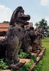 Löwenartige steinerne Wächterfiguren um die Basis der Stupa