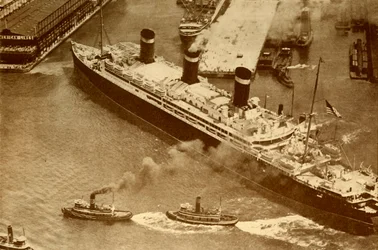 Ein Luftbild der Leviathan, die von kleinen Schleppern in ihr Dock in New York geschleppt wird, um 1930