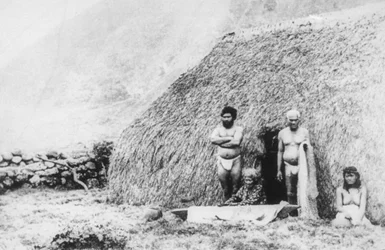 Eine alte Frau schlägt Tapa vor einem Pili-Grashaus, Kalaupapa, Hawaii, 19. Jahrhundert