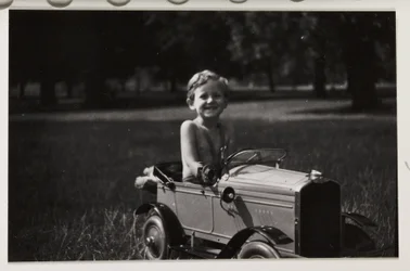 Junge fährt ein Spielzeug-Tretauto, um 1930