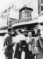 Deutsche Soldaten unterhalten sich mit französischen Frauen vor dem Moulin Rouge, besetztes Paris, Juni 1940