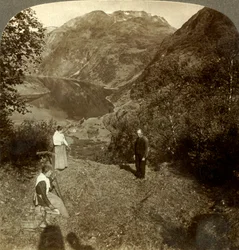 Heuernte auf einem Bergplateau hoch über dem Dorf Marok und dem spiegelklaren Geirangerfjord, Norwegen, um 1905