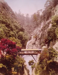 Überdachte Brücke in einer steilen Schlucht, mit Wasserfällen im Hintergrund, Japan, ca. 1890-1910