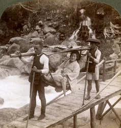 Japanische Frau in einem Yamakago-Bergstuhl überquert den reißenden Daiya-Fluss in der Nähe von Nikko, Japan
