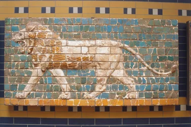 Asien, Türkei, Istanbul, Löwenrelief auf Ziegelwand gemalt, Seitenansicht eines wilden gelben Löwen mit großer Mähne, der vor grünem Hintergrund läuft.