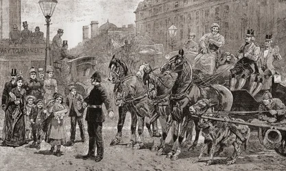 Ein Polizist stoppt den Verkehr an einer belebten Kreuzung, um Fußgängern das Überqueren der Straße zu ermöglichen, London, England