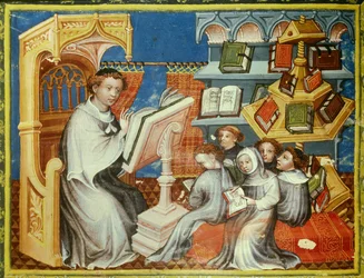 Klosterschule des Augustiner-Eremitenklosters in Paris: Ein Mönch liest eine Lektion von einer Kanzel vor Jugendlichen mit Tonsuren, aber auch Laien. Rechts ein Pfundrad. Miniatur in „Bible historiale“ von Pierre Comestor