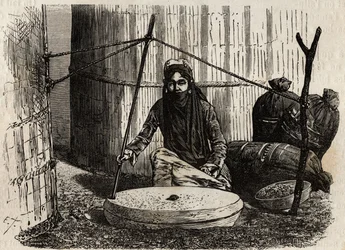 Turkmenische Frau benutzt das Getreidemahlrad, aktiviert ein raffiniertes Kurbel-System. Gravur zur Illustration der Reise nach Japan 1863-1864 von Aime Humbert, Minister der Schweizerischen Eidgenossenschaft