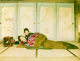 Auf einem Futon liegend. Zwei japanische Frauen liegen auf einem traditionellen Futon auf dem Boden. Japan, um 1910.