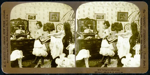 Stereoskopische Karte, die eine Frau zeigt, die in ein Korsett geschnürt wird, ca. 1900