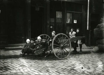 Gruppe von Kindern im Wagen, mit Mädchen und Frau dahinter, ca. 1910-21