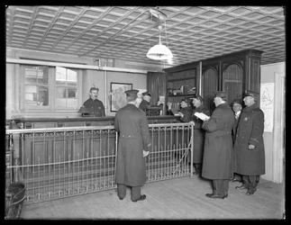 Innenansicht einer nicht identifizierten Polizeistation, zeigt Beamte und Empfangstresen, ca. 1913-14